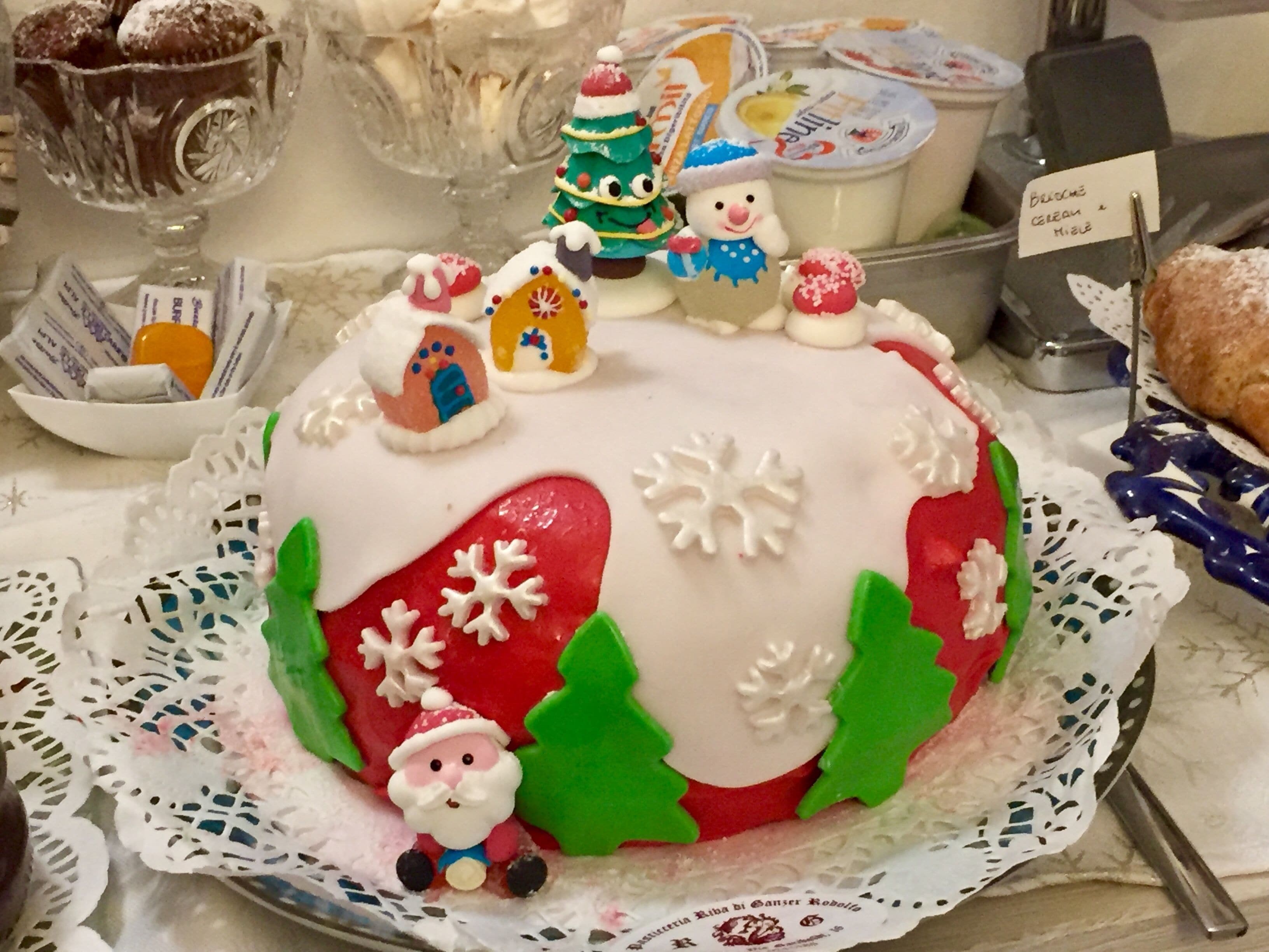 Un gâteau festif décoré de flocons de neige, d’un petit Père Noël et de sapins de Noël.