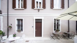 A building with a brown door, white-framed windows, and a white balcony with white chairs and tables. - Residenza Elisa (Desenzano del Garda)