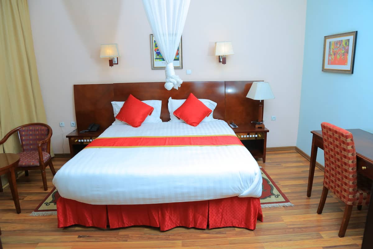 Une chambre d’hôtel avec un grand lit, deux tables de chevet, un bureau et une chaise.