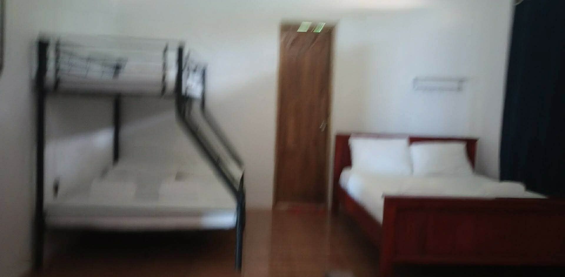 A room with a bunk bed, a single bed, and a door.