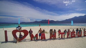 A group of people standing in front of a large heart-shaped sign with the text "I LOVE MANTIGUE." - Seaside Travelers Inn by Camiguin Island Home (Catarman)