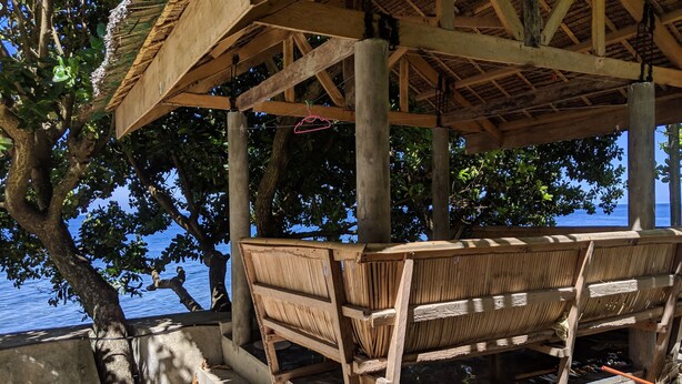 A wooden structure with a bench, concrete steps, and a view of the sea. - Seaside Travelers Inn by Camiguin Island Home (Catarman)