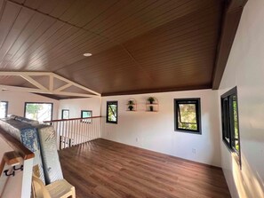 A spacious room with a high ceiling and wooden beams, large windows, and a view of greenery outside. - Seaside Travelers Inn by Camiguin Island Home (Catarman)