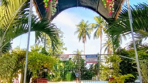 A covered entrance with a gate, potted plants, and palm trees. - Seaside Travelers Inn by Camiguin Island Home (Catarman)