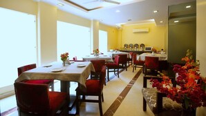 A dining area with multiple tables, chairs, and a ceiling fan. - Hotel Ivory Palace (New Delhi)