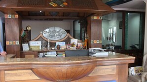 A reception desk with a wooden design, a clock, and various items on the counter. - Hotel Ivory Palace (New Delhi)