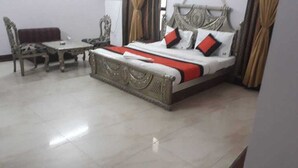 A neatly arranged bedroom with a bed, a small table, and a chair. - Hotel Ivory Palace (New Delhi)