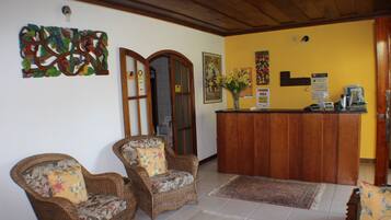 A reception area with wicker chairs, a wooden reception desk, and a floral vase.