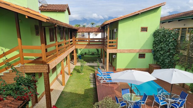 A courtyard with a swimming pool, outdoor seating, and a view of mountains. - Pousada Flor de Paraty (Paraty)