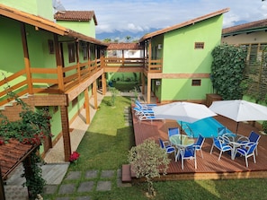 A courtyard with a swimming pool, outdoor seating, and a view of mountains. - Pousada Flor de Paraty (Paraty)