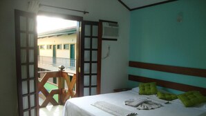A bedroom with a bed, green pillows, a white bedspread, and a wooden headboard. - Pousada Flor de Paraty (Paraty)
