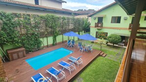 A backyard with a swimming pool, blue lounge chairs, and umbrellas. - Pousada Flor de Paraty (Paraty)