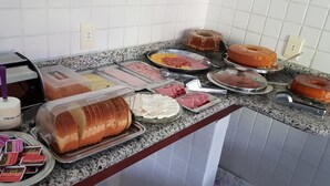 A buffet table with various food items including bread, meats, and pastries. - Pousada Flor de Paraty (Paraty)