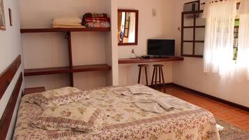 Un dormitorio con cama, escritorio, televisor y ventana con cortinas.