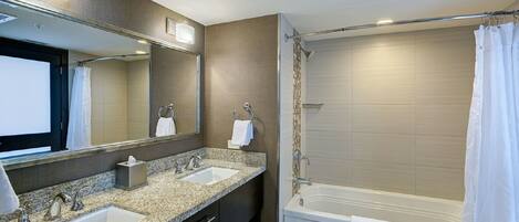 A modern bathroom with two sinks, a large mirror, a bathtub, and a shower curtain.