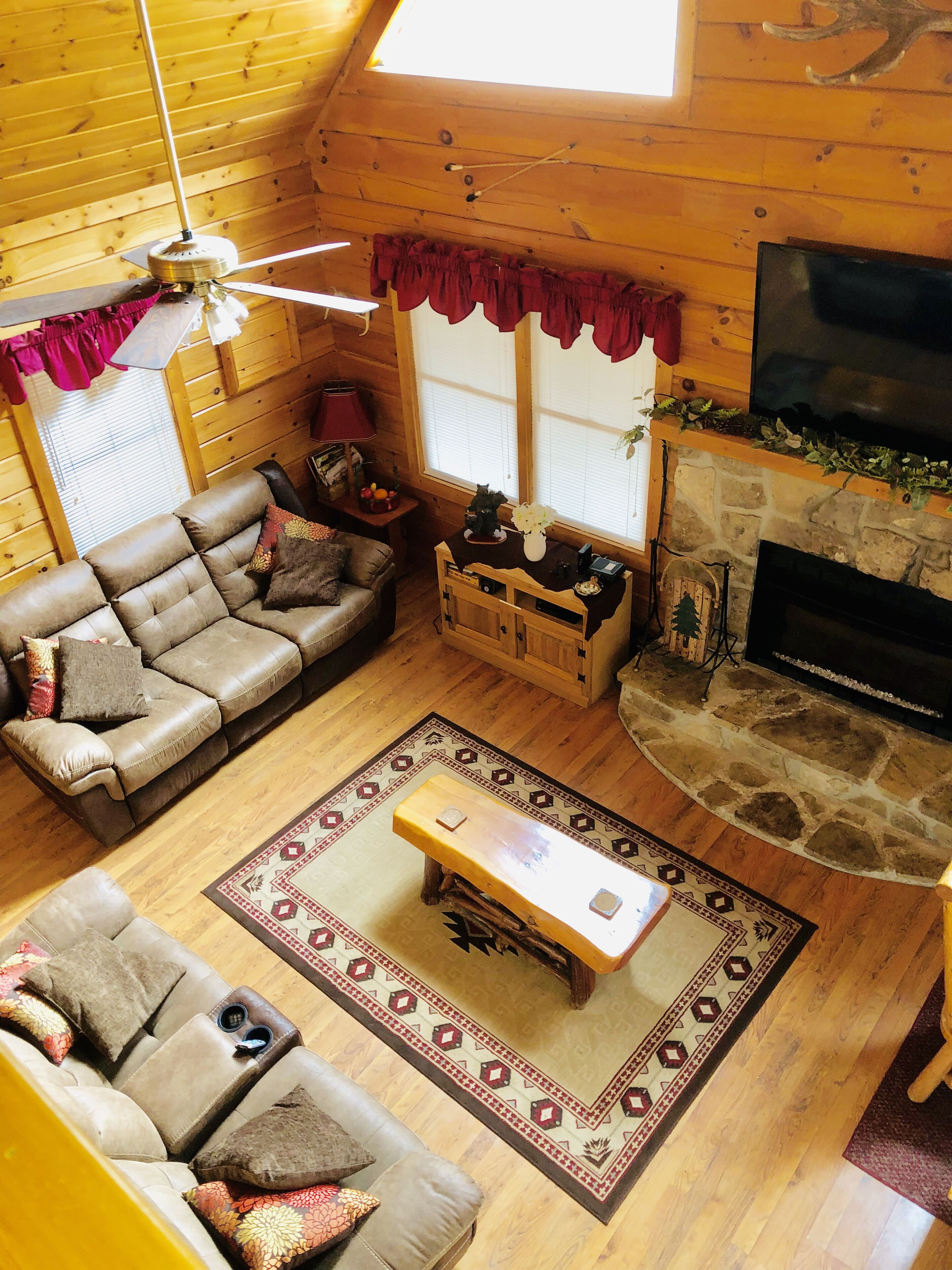 L’intérieur d’un chalet confortable, avec des murs en bois, un canapé, une table basse, une cheminée et un téléviseur.