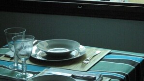 A table set with plates, glasses, and cutlery, with a view of a canal and gondolier in the background. - Ca Vecchio Pozzo:Charming property in central historical Venice (VENICE)