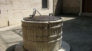 A large, ornate stone well with intricate carvings, situated on a paved area with a building in the background. - Ca Vecchio Pozzo:Charming property in central historical Venice (VENICE)