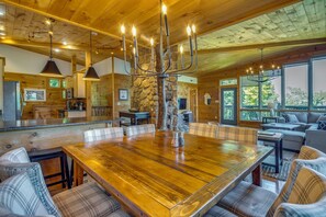 Une salle à manger spacieuse avec une grande table en bois, des chaises à carreaux et un chandelier.