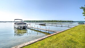 Un lac paisible, avec un quai et un bateau à ponton abrité.