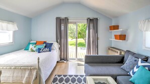 Une chambre à coucher avec un lit, un canapé, une fenêtre avec des rideaux et une vue sur l’extérieur.