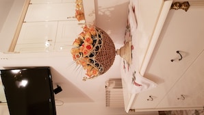 A white cabinet with a decorative basket of flowers, a television, and a patterned wall.