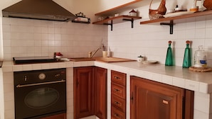 A kitchen with white tiles, wooden cabinets, a stove, and a sink.
