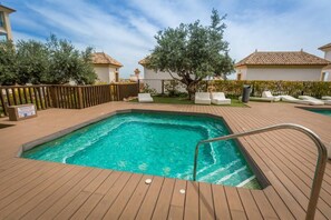 A rectangular swimming pool with a wooden deck, surrounded by lounge chairs and a wooden fence. - Fidalsa Guardamar Resort (Guardamar)