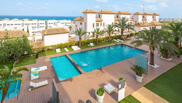 A rooftop pool with lounge chairs, palm trees, and a view of the sea. - Fidalsa Guardamar Resort (Guardamar)