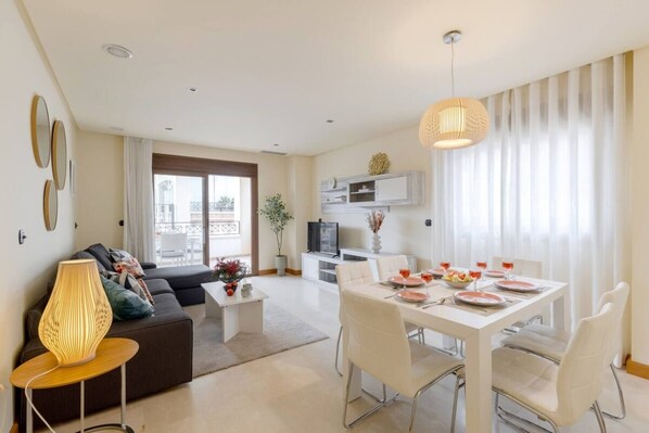 A modern living room with a sofa, coffee table, and dining area set for a meal.