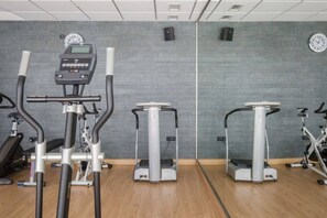 A gym with cardio machines, a mirrored wall, and a clock.