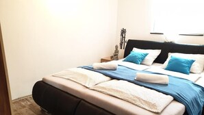 A bed with a black headboard, a blue and white bedspread, and multiple pillows.