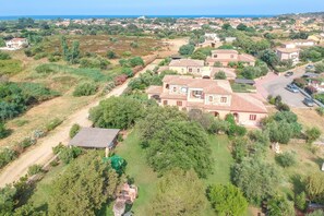 An aerial view of a residential area with houses, greenery, and a clear sky.