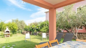 Un patio al aire libre con una mesa, sillas, un muro de piedra y un horno para pizza.