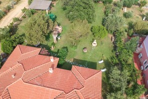 An aerial view of a residential area with a red-tiled roof, green lawns, and trees.