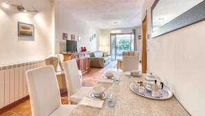 A dining area with a table set for four, a sofa, a TV, and a view of the outdoors.