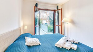 A hotel room with a bed, a window, and a view of the outside.