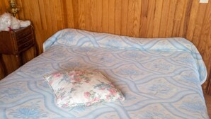 A bed with a floral-patterned bedspread and a single decorative pillow. - Homerez - House in Orsanco (Orsanco)