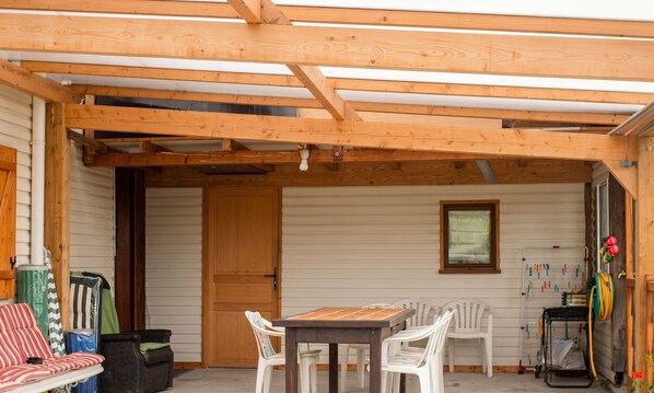 A wooden deck with a table and chairs, a door, and a window. - Homerez - House in Orsanco (Orsanco)