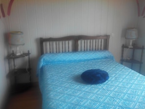 Quarto com cama, mesa de cabeceira, abajur e uma cadeira.