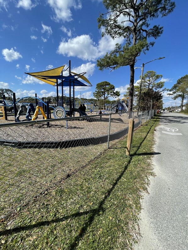 A playground with various play structures, a fenced area, and a bike lane.
