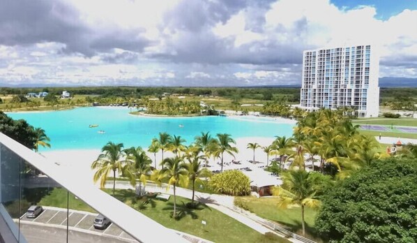 A resort with a large pool, palm trees, and a tall hotel building.