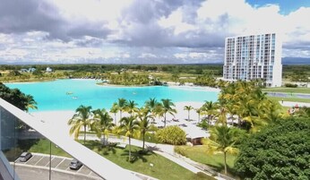 A resort with a large pool, palm trees, and a tall hotel building.