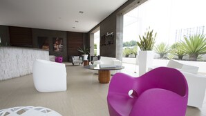 A modern living room with white and purple furniture, a round coffee table, and a view of the outdoors. - Apartamento en Playa Blanca Town Center (Rio Hato)