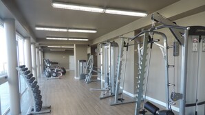 Un gimnasio con diversos equipos de ejercicio, como mancuernas, cintas de correr y máquinas de pesas.