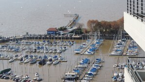 Un puerto deportivo con numerosas embarcaciones amarradas, un muelle que se adentra en el agua y un edificio con tejado rojo.
