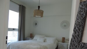 Un dormitorio con una cama, dos mesitas de noche, una lámpara colgante y espejos decorativos en la pared.