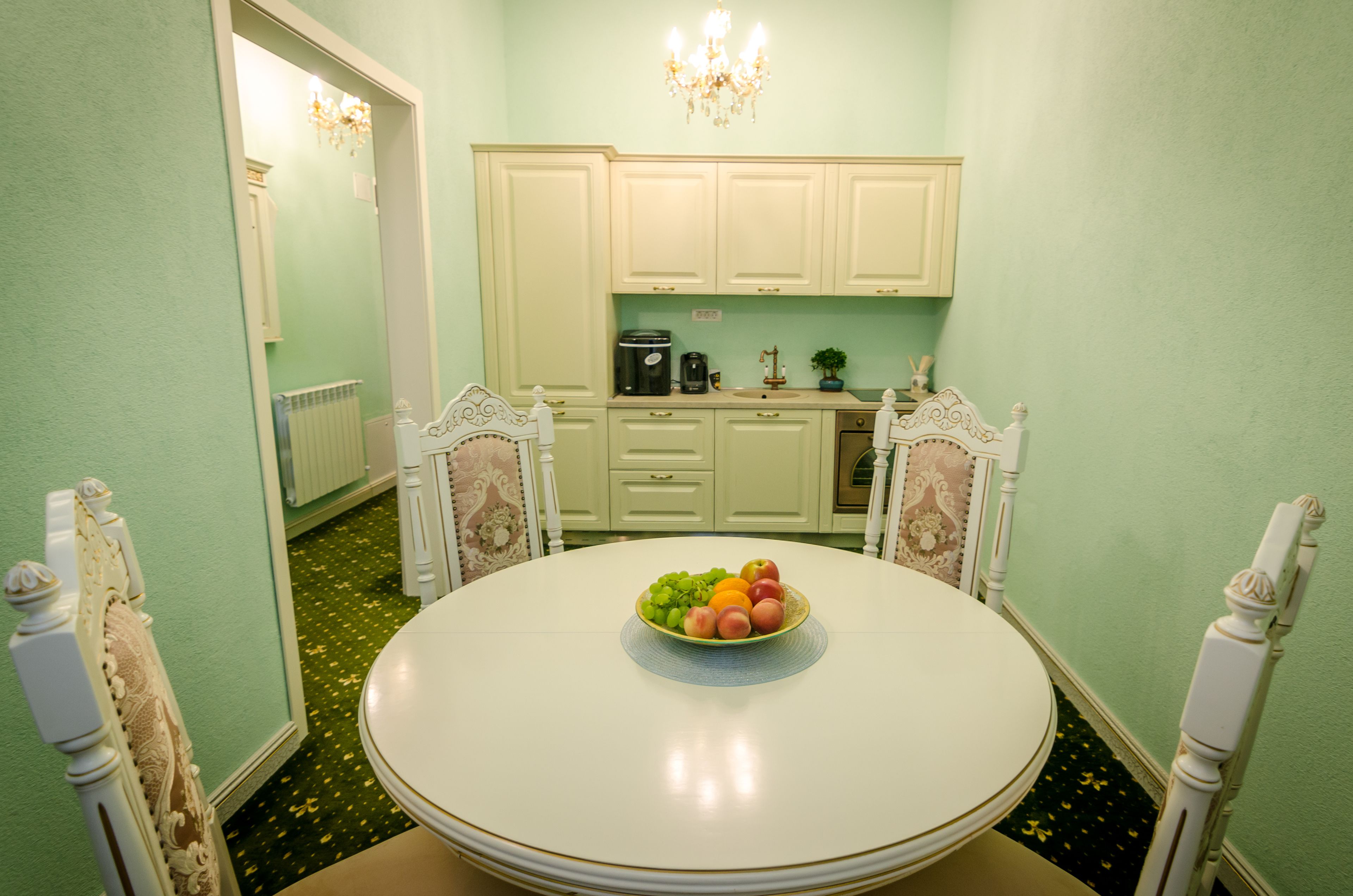 Een eethoek met een ronde tafel, stoelen en een schaal fruit.
