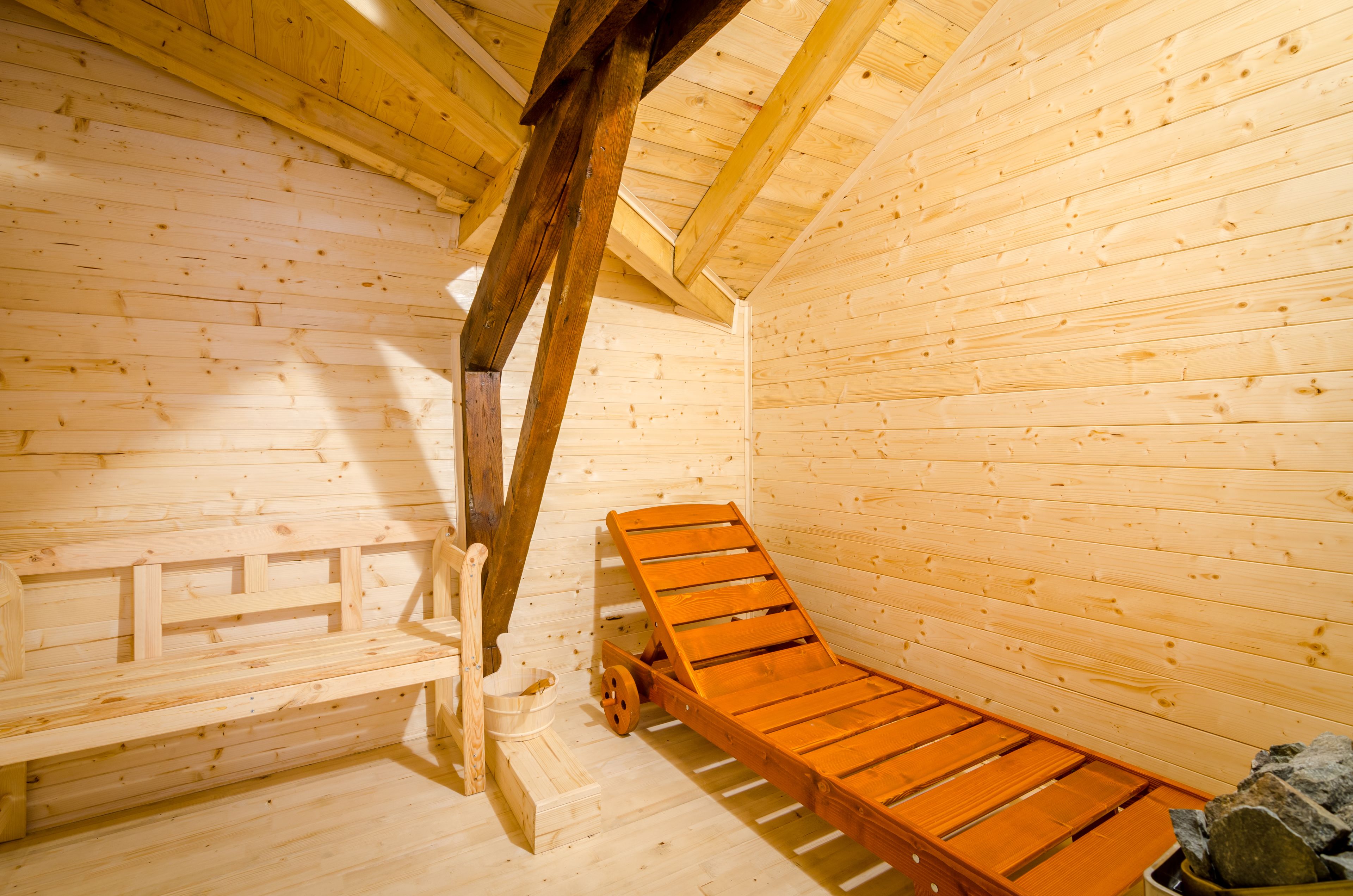 Un sauna de madera con bancos y estructura de techo de madera.