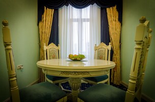 A dining area with a round table, two chairs, and a bowl of fruit.